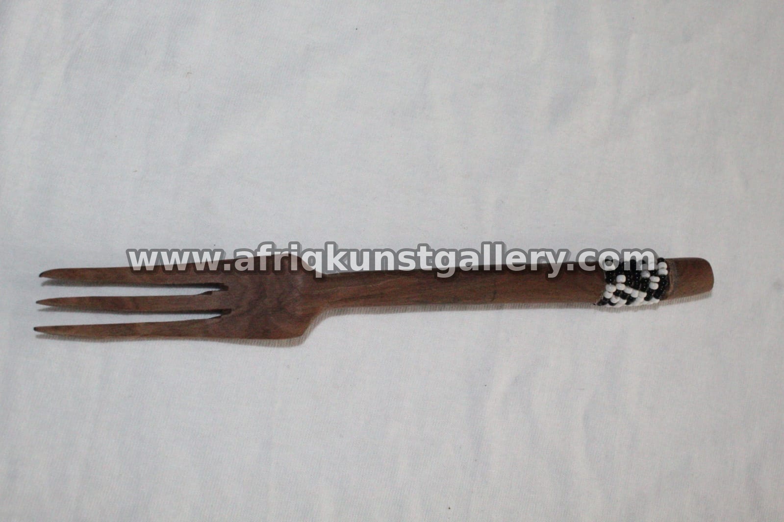 Wooden serving fork with a beaded handle detail.