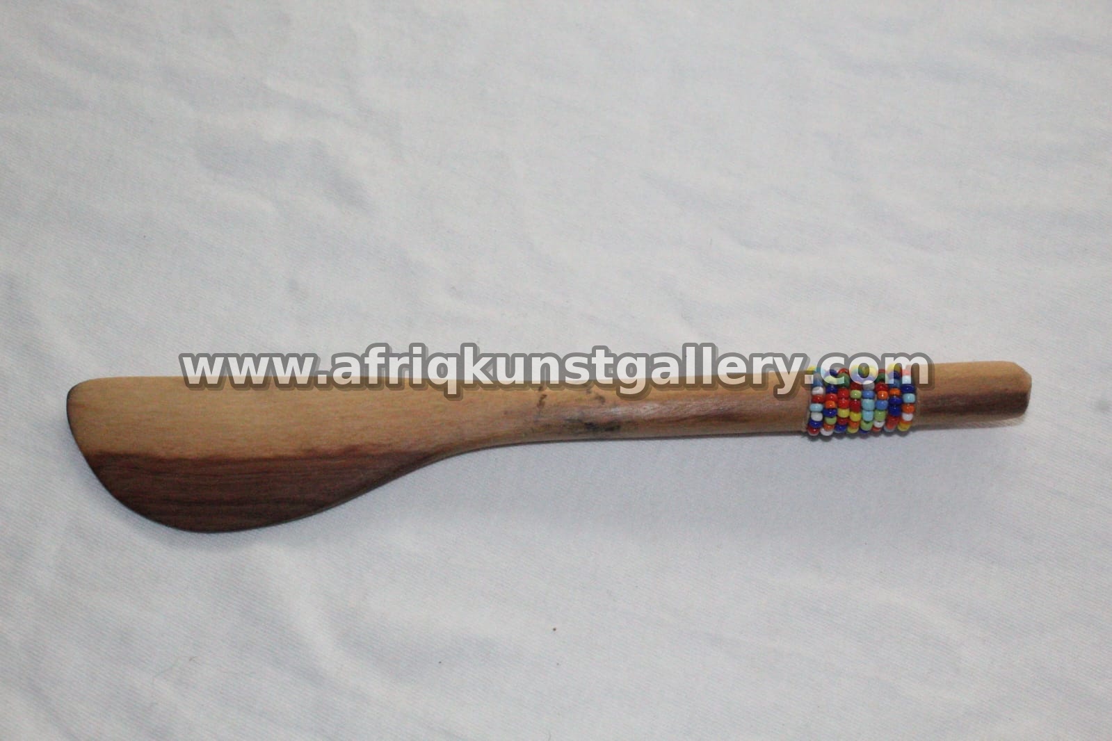 Wooden serving spatula with a small beaded handle detail.